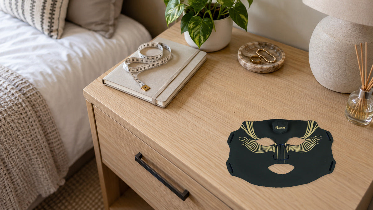 An original black-and-gold mask resting on a bedside wooden table beside a measuring tape and notebook.