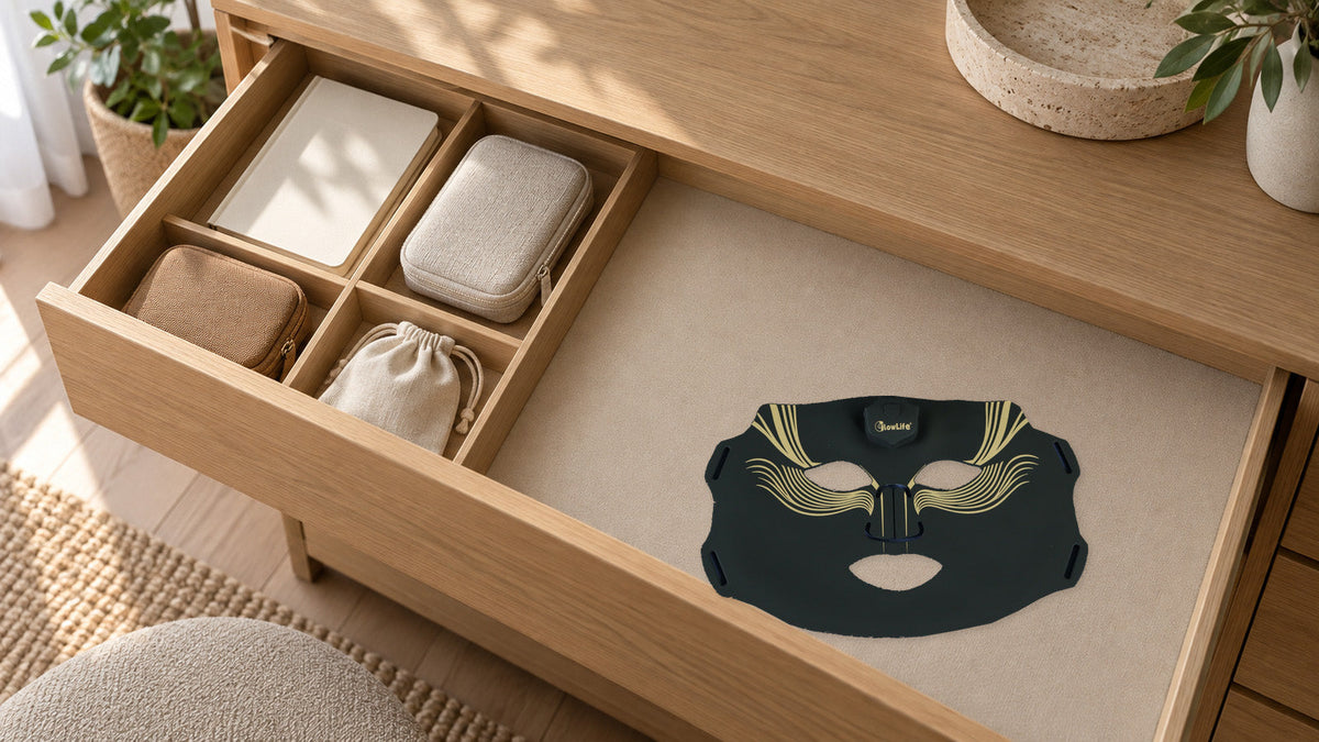 An original black-and-gold mask resting on a lined drawer beside separate accessory pouches and a notebook.
