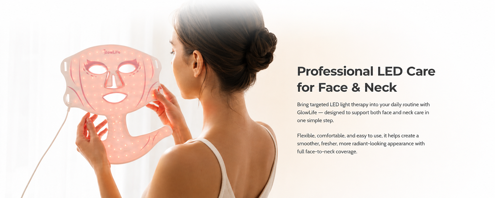 VanqHeal face and neck LED light therapy mask glowing red as a woman holds it beside a bright window