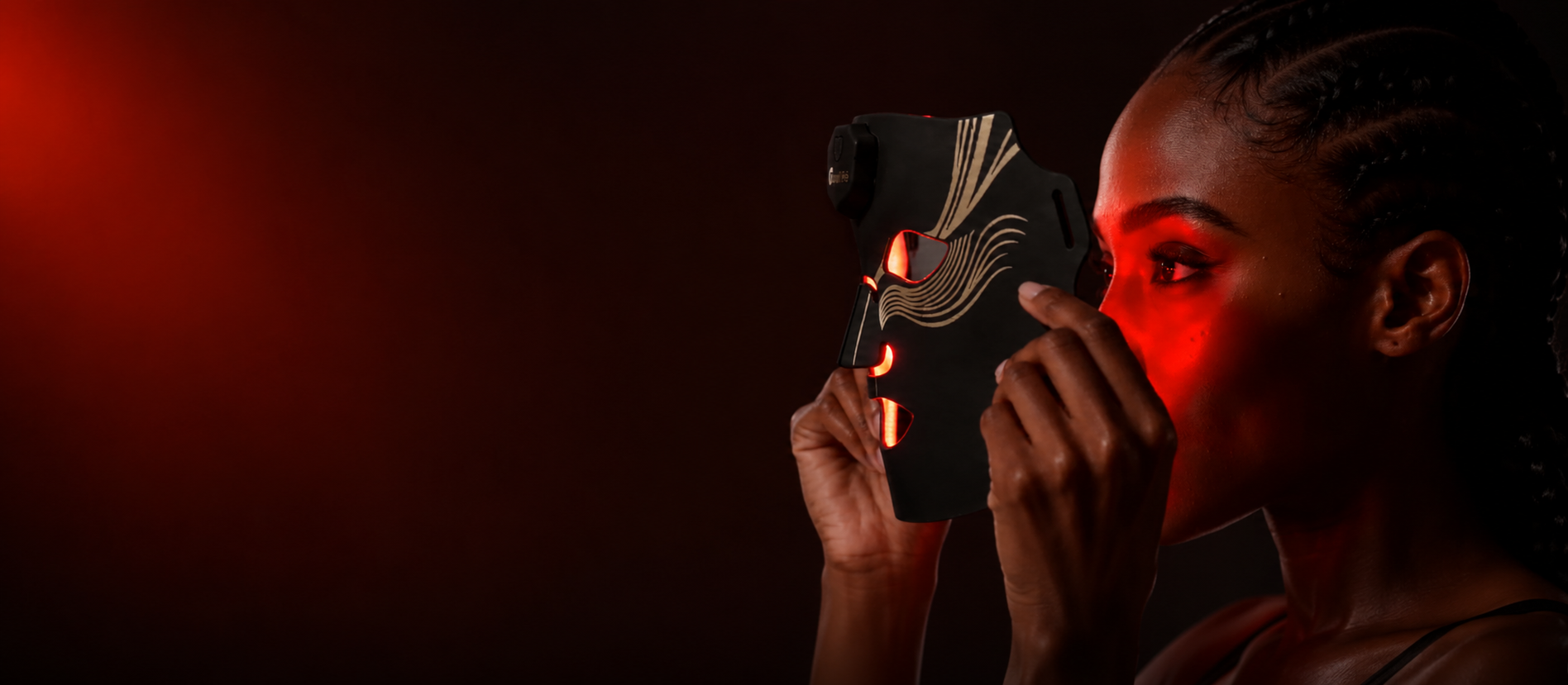 VanqHeal about page hero with a woman holding a black red-lit LED face mask for at-home skincare